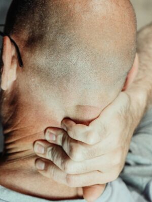 A bald man holding his neck to soothe discomfort, highlighting neck pain relief methods.
