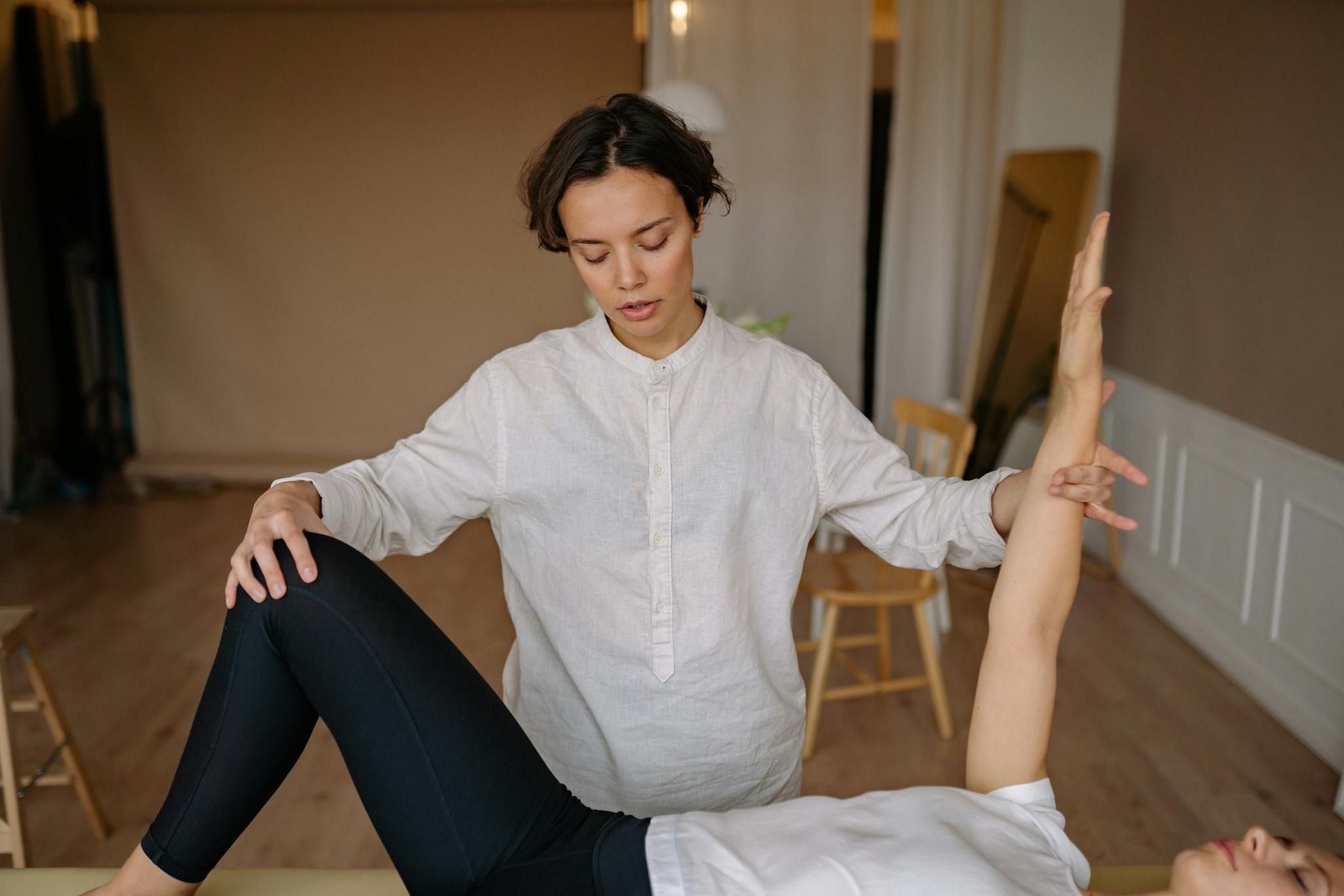 A chiropractor assists a patient during a therapy session indoors.