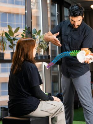 Chiropractor demonstrating spine anatomy to a patient during consultation indoors.